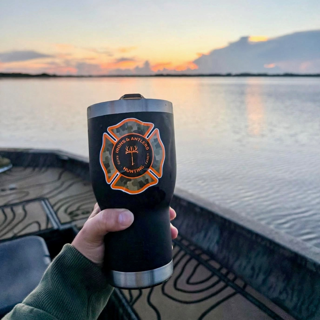 Irons and Antlers tumbler held over a boat at sunset